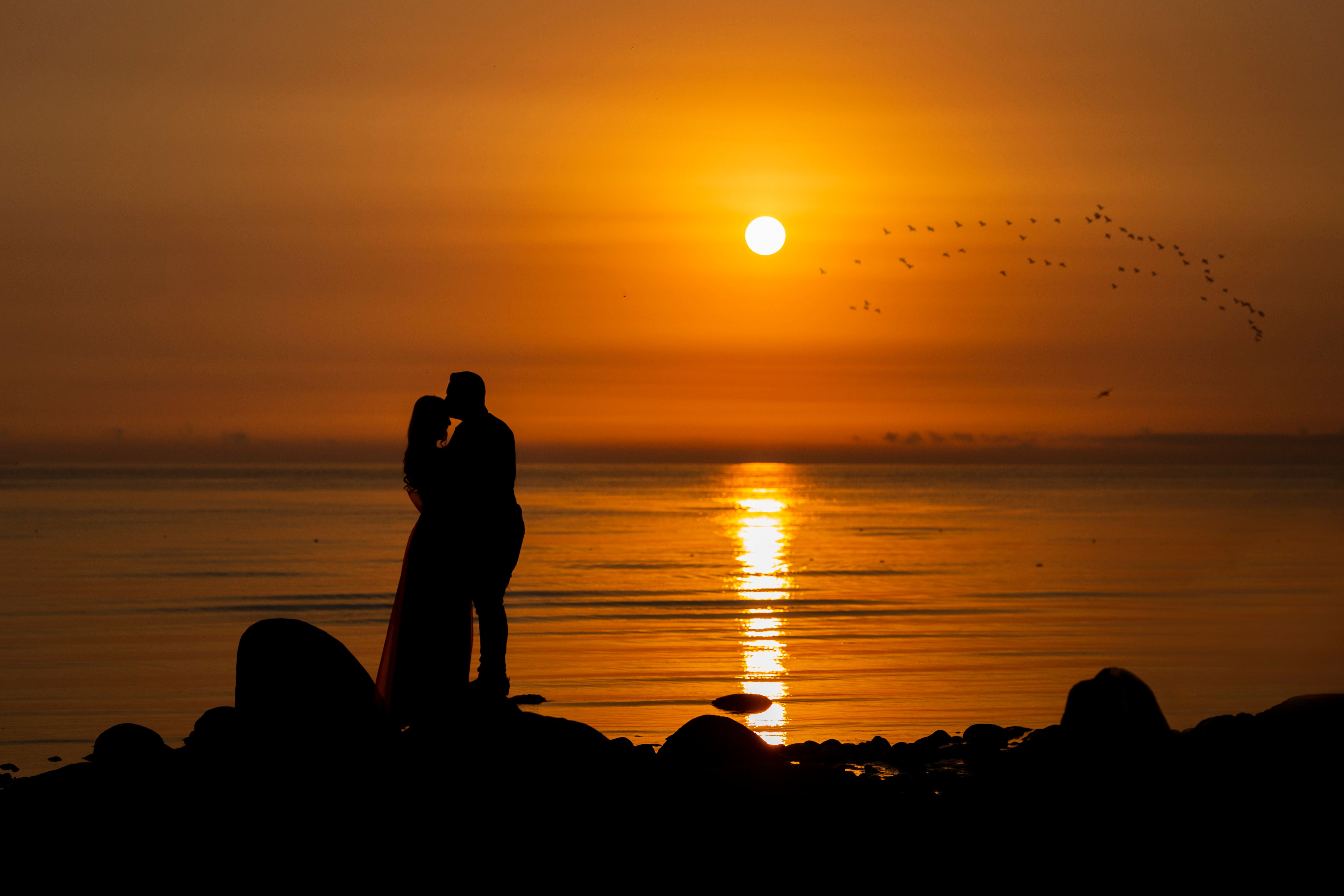 Silhouette of a Romantic Couple on Rocky Shore · Free Stock Photo
