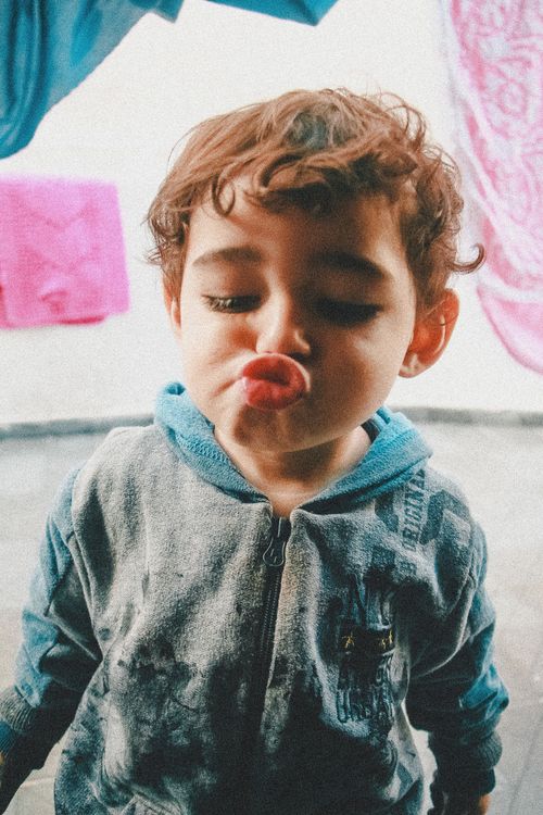 Free Cute young child playfully puckering lips for a funny face indoors, capturing a moment of joy. Stock Photo