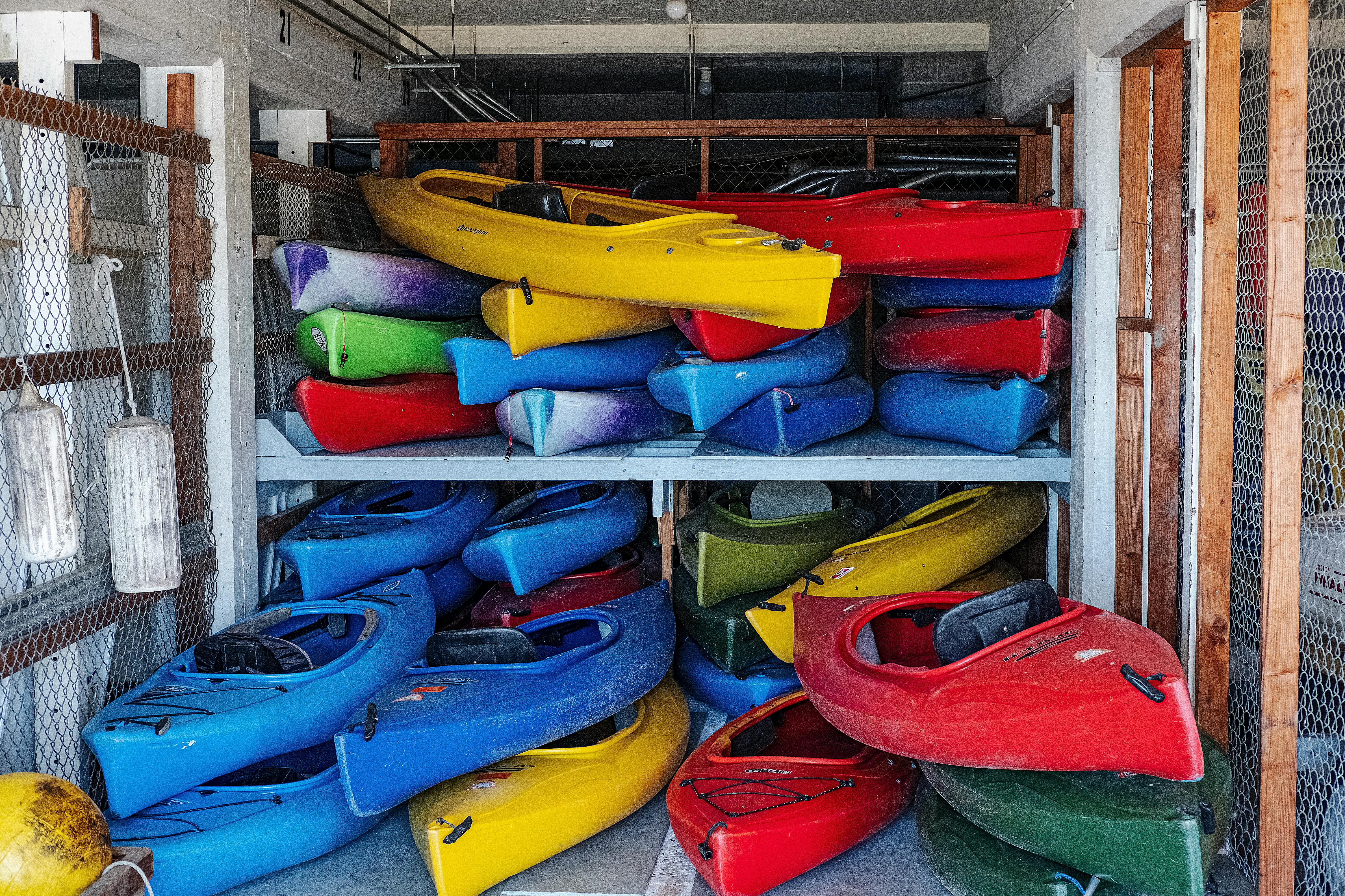 Colorful kayaks stacked in an indoor storage area, showcasing vivid designs.