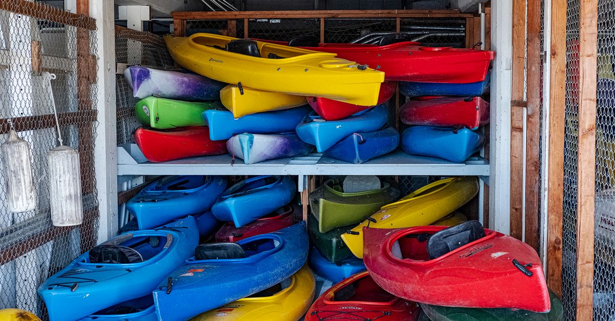 Colorful kayaks stacked in an indoor storage area, showcasing vivid designs.