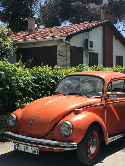Free Vintage orange Volkswagen Beetle parked in front of a house in Urla, İzmir, Turkey. Stock Photo