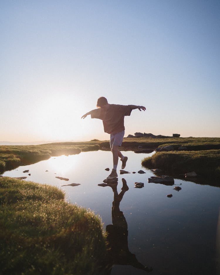 Man Jumping On Rocks Over A River