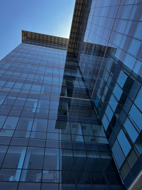 Free Low angle view of a modern glass facade building against a blue sky in Cuernavaca, Mexico. Stock Photo