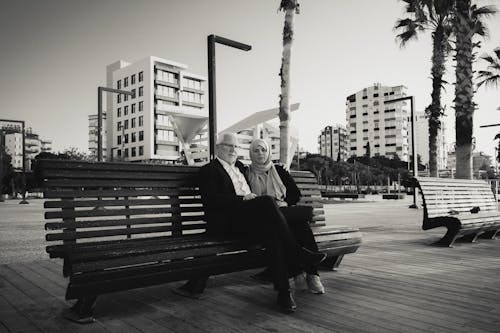 Grayscale Photograph of a Couple Sitting on a Bench