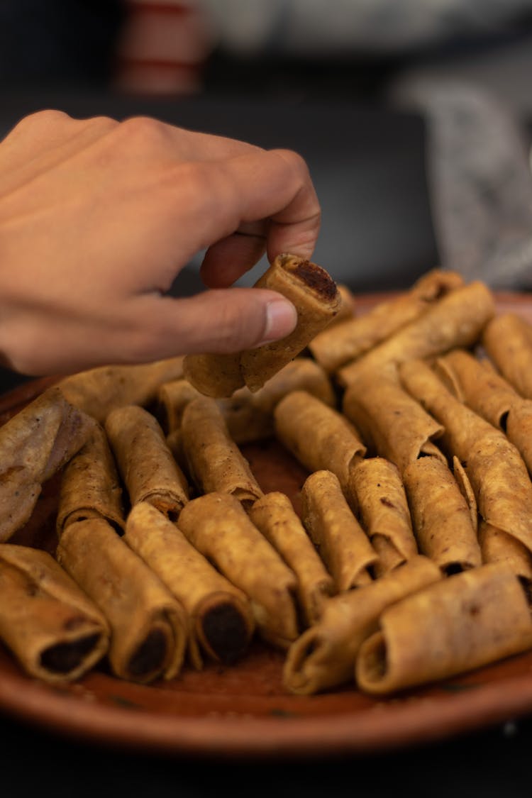 A Person's Hand Getting A Taquito