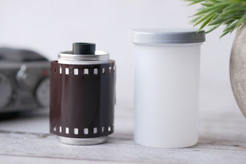 Free Close-up of a vintage camera film roll and plastic container on a wooden table. Ideal for photography nostalgia. Stock Photo