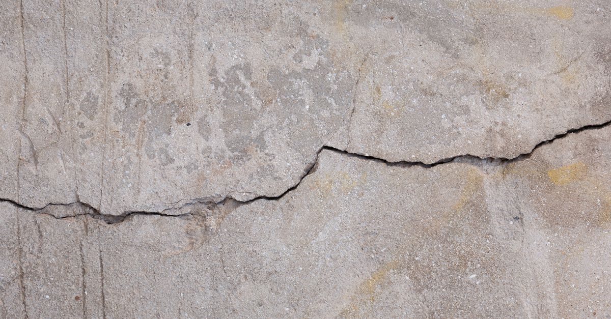 Verwitterte Betonwand mit feinen Rissen und unregelmäßiger Oberflächenstruktur