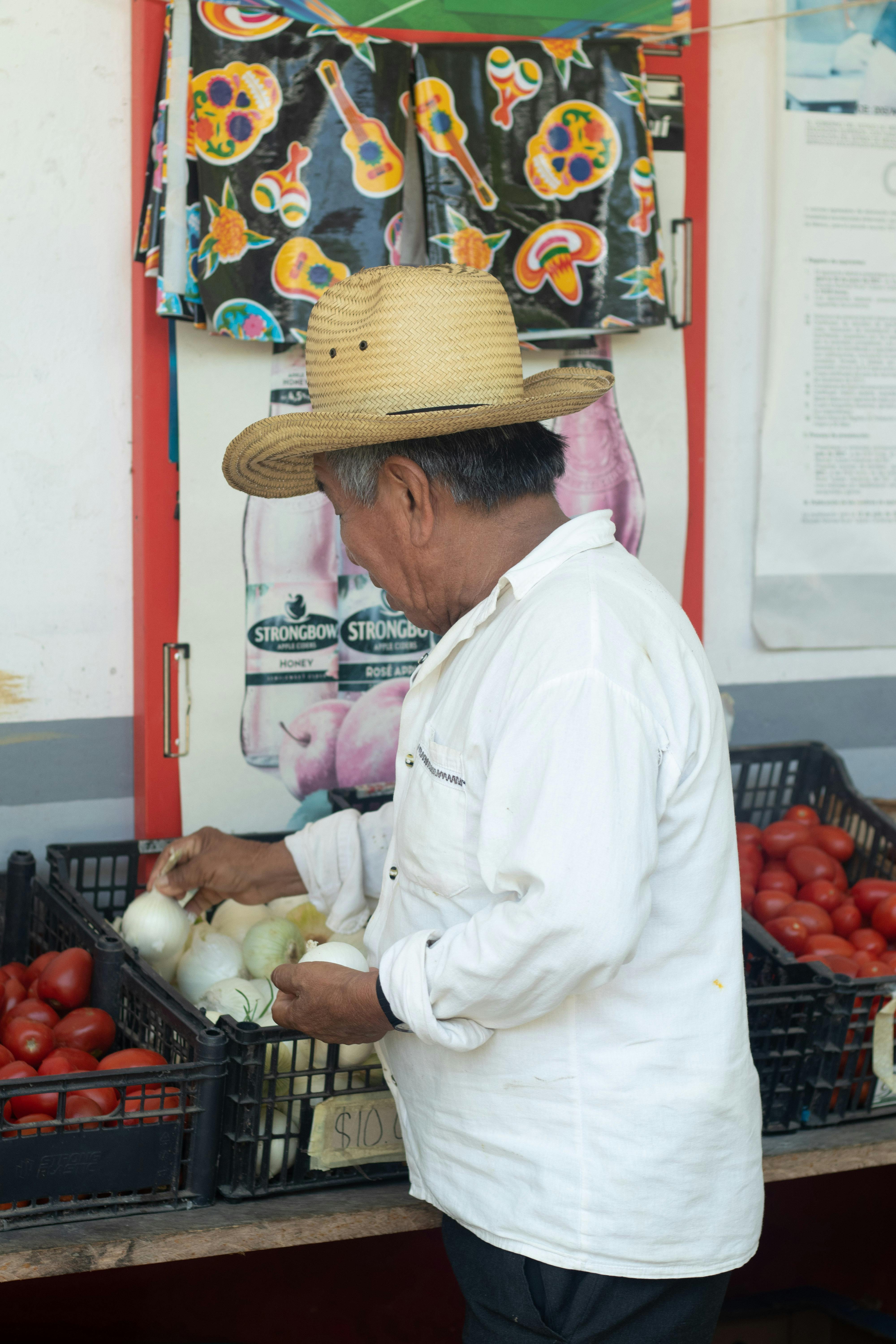 Man with a Hat Getting Onions from a Basket · Free Stock Photo