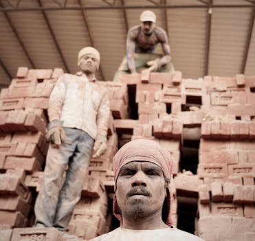 Three men working at a brick construction site, conveying industrial labor.