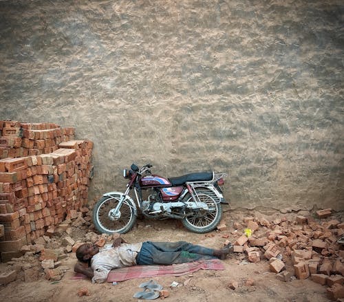 A Man Lying Beside a Motorcycle