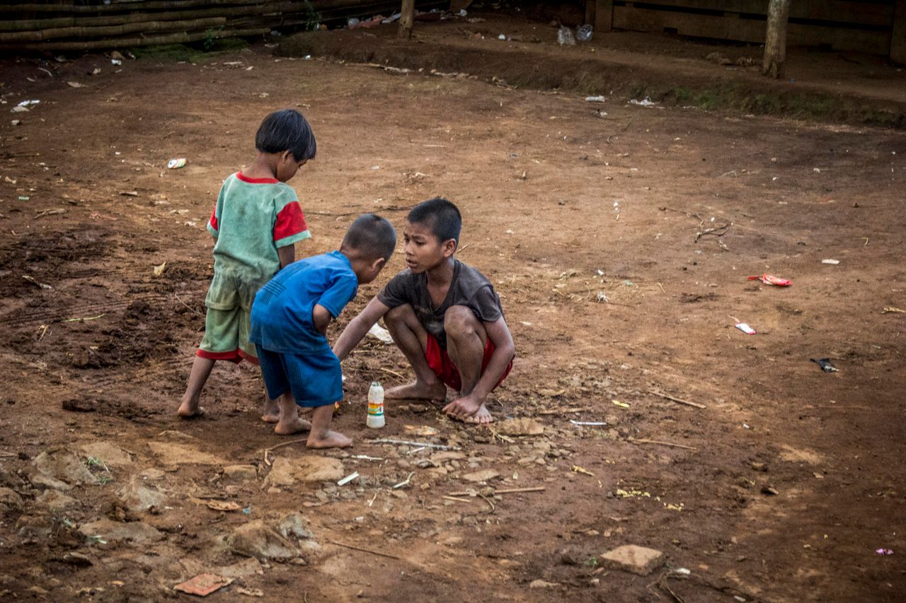 three young children playing on a dirt path depicting playful interact