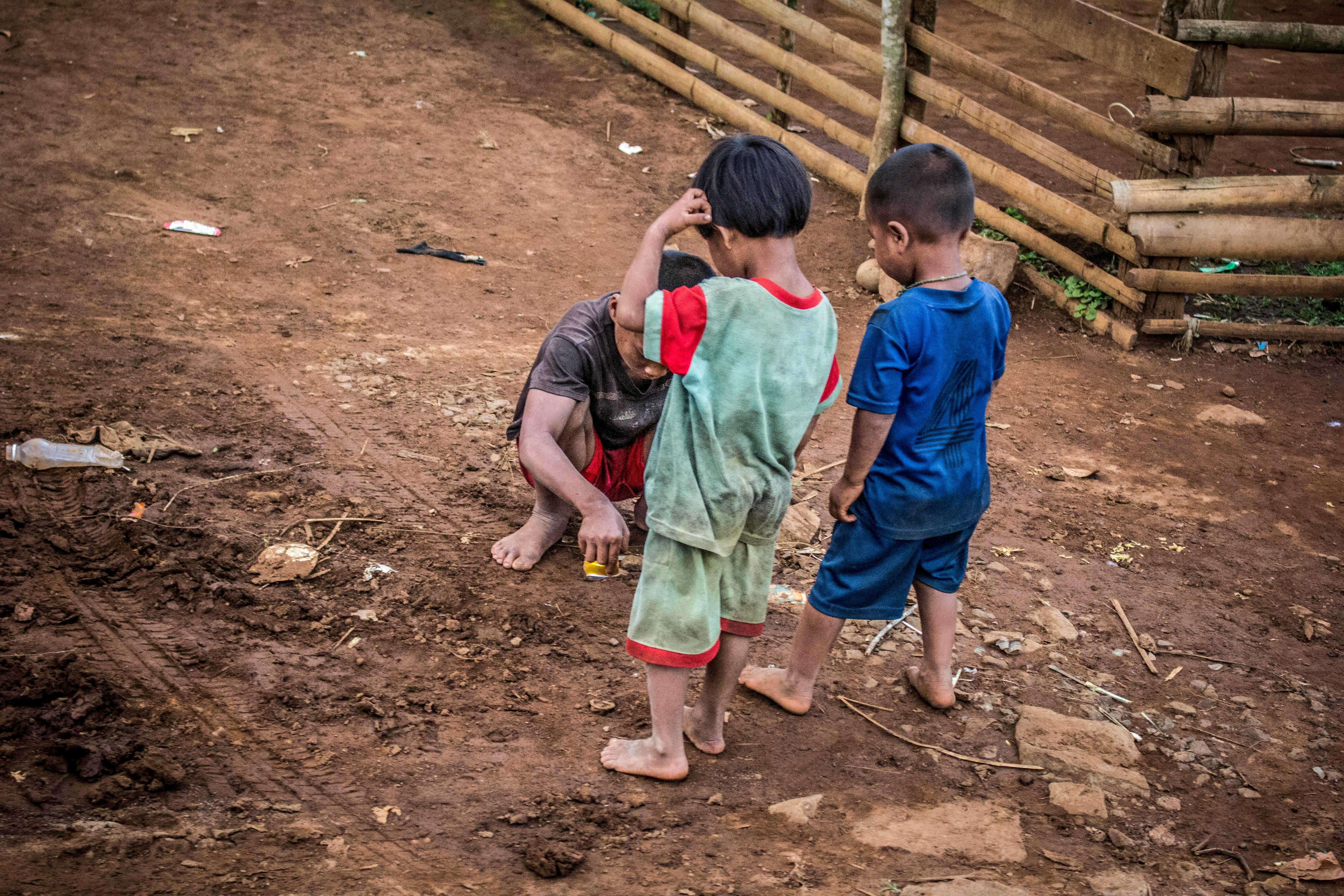 three children standing on brown soil