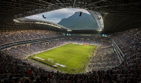 A vibrant football match at Estadio BBVA with a backdrop of Cerro de la Silla, Monterrey.