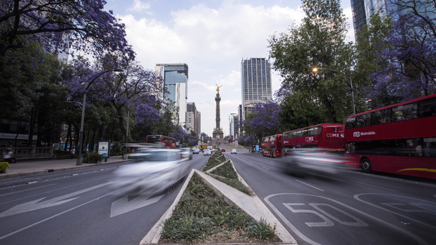 Night view of Angel of Independence in bustling Ciudad de México with blurred traffic.