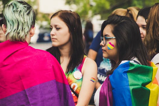 A vibrant group of young adults at an LGBTQ+ pride parade with rainbow flags and face paint.