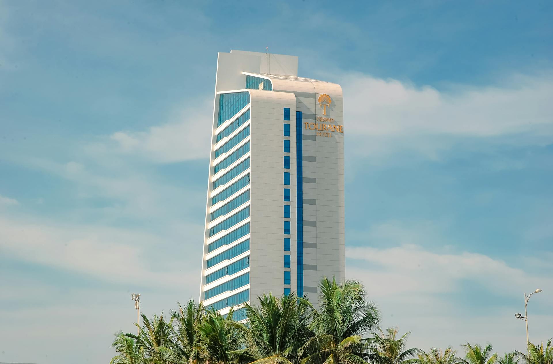 High-rise modern building with palm trees and clear blue sky. Ideal for travel and business themes.