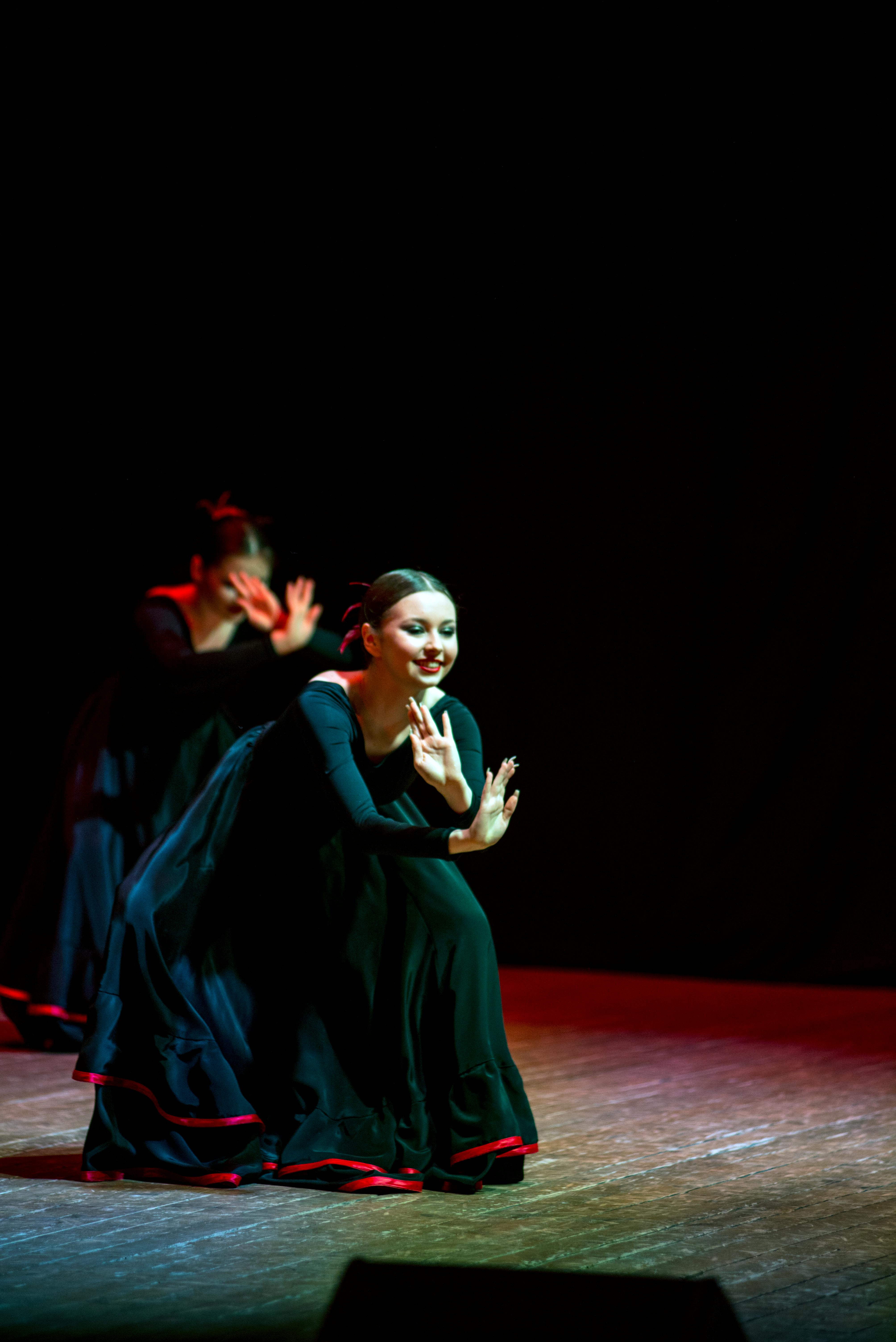 Free A graceful dancer performing in a black dress during a folk dance show on stage. Stock Photo