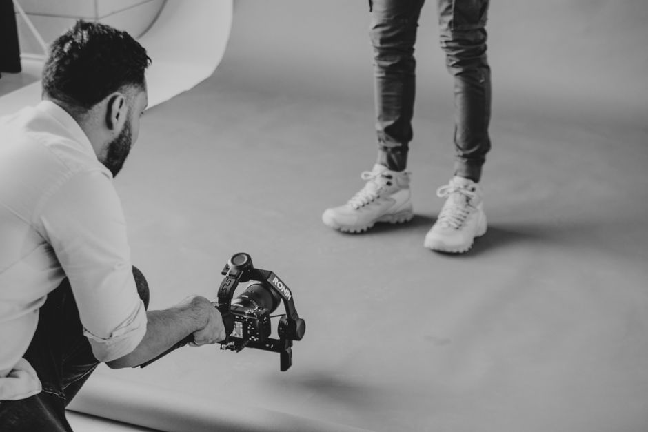 UPPAbaby Vista V3 vs Nuna MIXX Next: Growing Family Stroller Face-Off Photographer with video stabilizer captures studio shoot in monochrome.