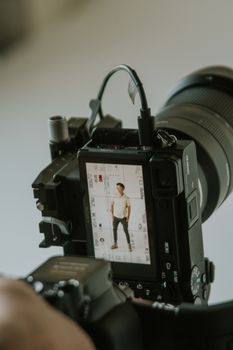 Close-up of camera screen capturing male model during indoor photo shoot.