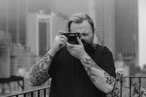 Free Black and White Portrait of Man Taking a Photo with a Camera Stock Photo