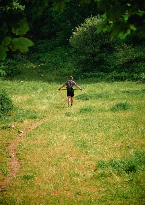 Free A lone hiker walks through a lush green field in Zhulat, Albania, enjoying nature's tranquility. Stock Photo