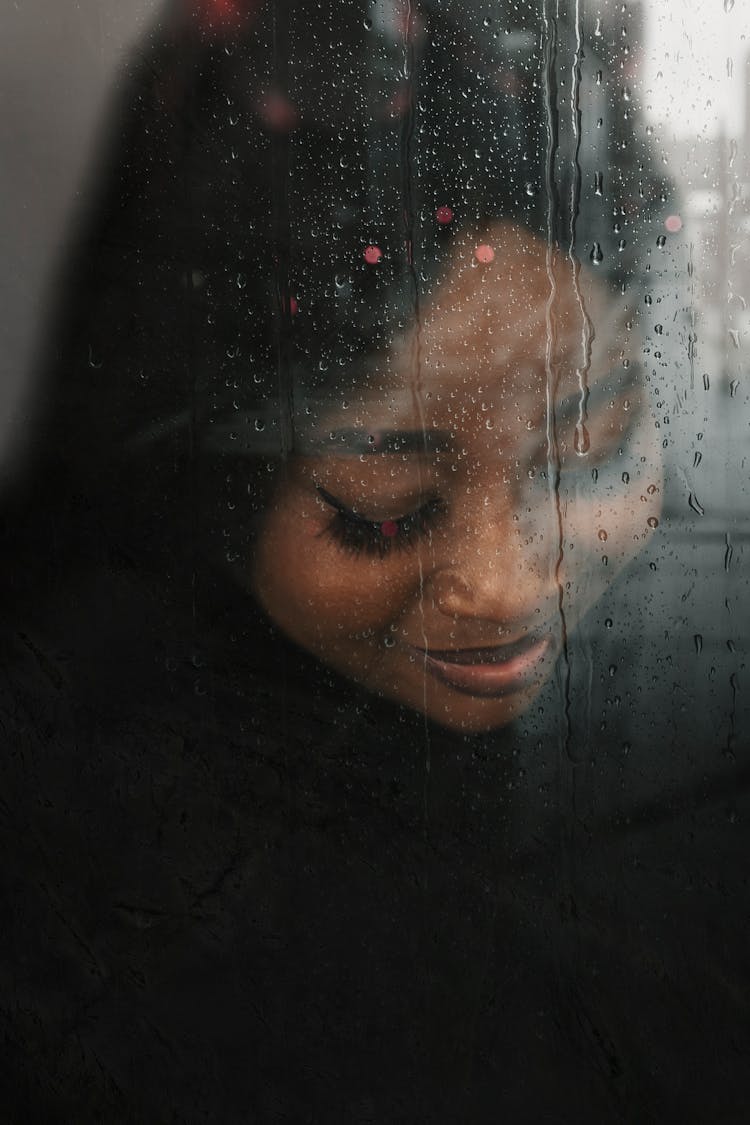 Face Of Young Smiling Woman Behind Window Pane