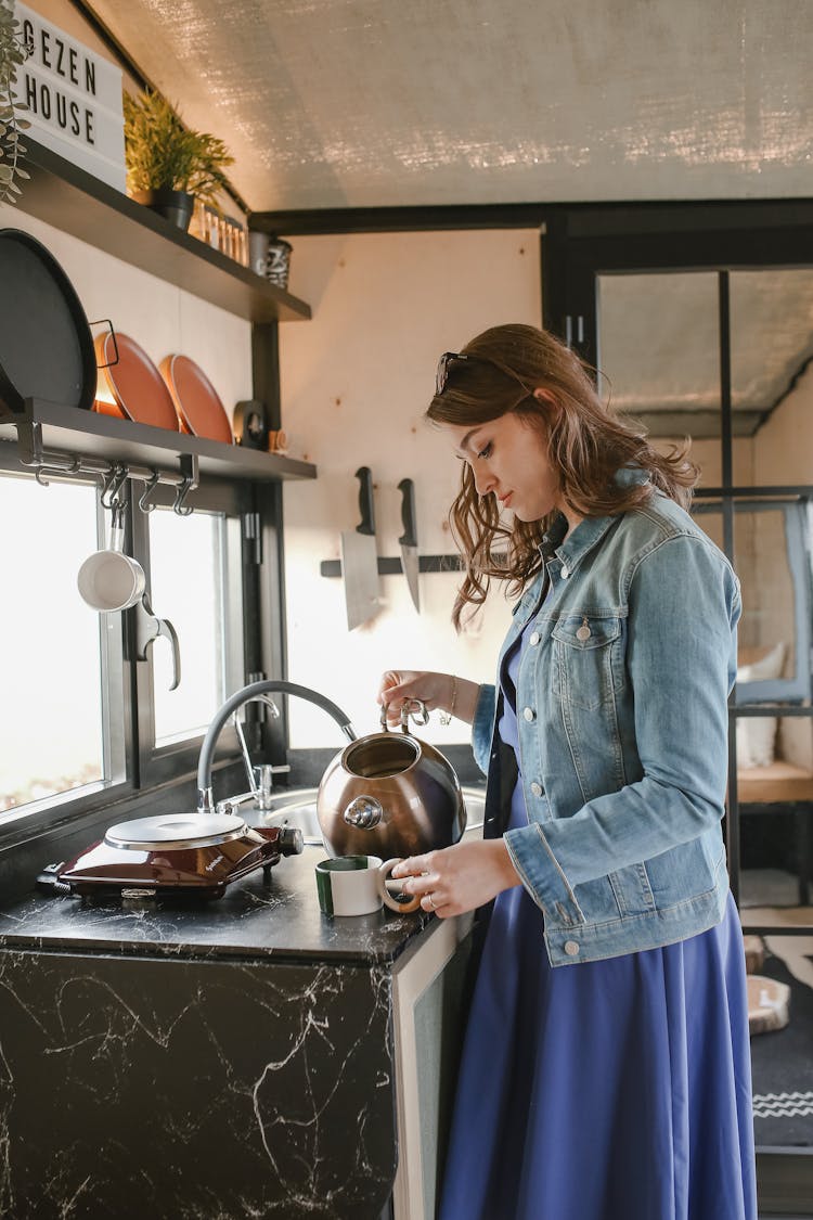 Woman Holding Kettle And Pouring Water To Cup