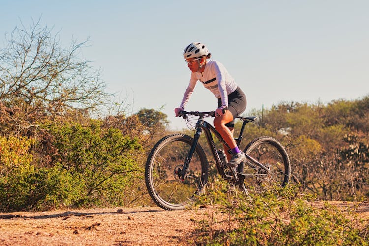 A Woman Riding A Bike On A Dirt Road