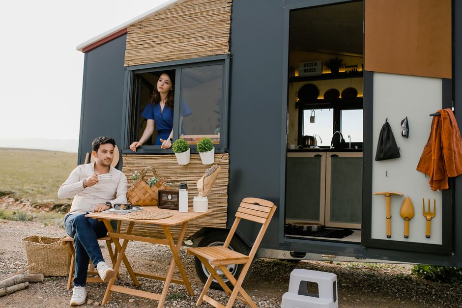 A couple enjoys a relaxing moment with coffee in front of their modern mobile home.