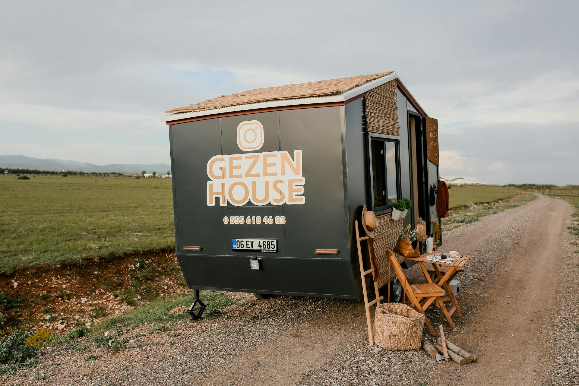 A modern mobile tiny house by a rural road in scenic countryside, ideal for off-grid living.