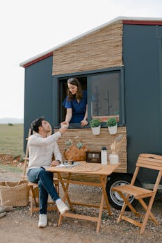 A couple sharing tea outside a mobile home with a cozy setup.