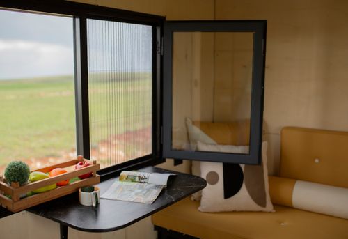 Free A charming tiny house interior with a window view of nature, featuring a compact dining area. Stock Photo