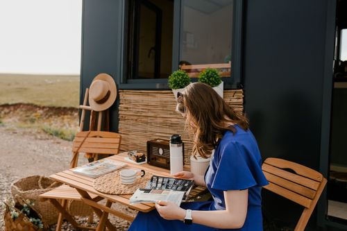 Free A woman enjoys reading a magazine at a cozy outdoor setup on a sunny day. Stock Photo
