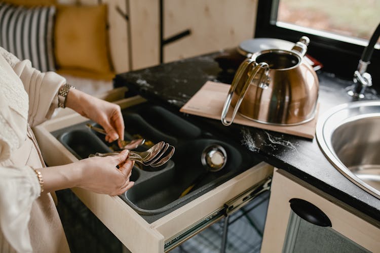 Unrecognizable Woman Putting Table Spoons In Drawer