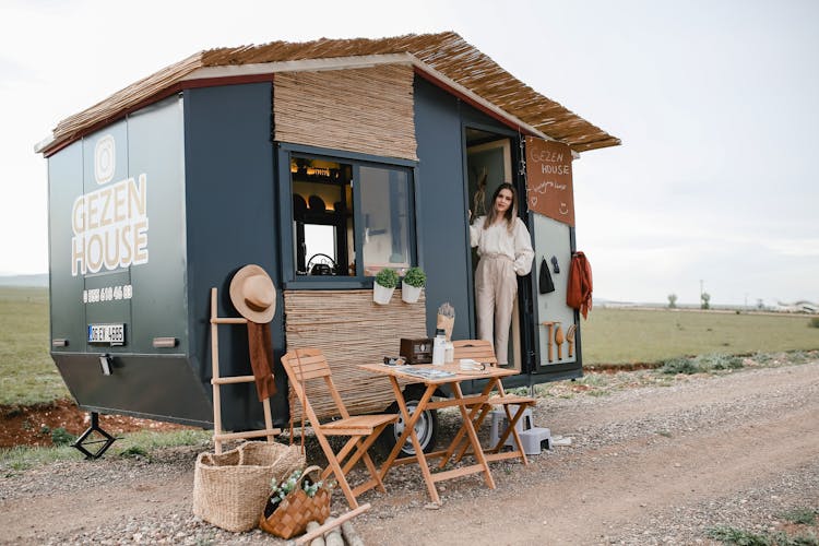 Woman Standing In A Trailer Converted To A House On Wheels 