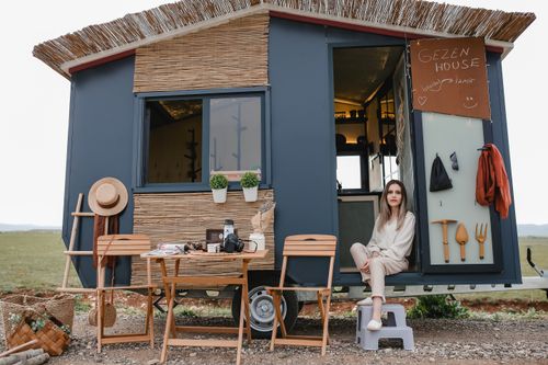 Free A woman relaxing outside her modern tiny mobile home in a scenic outdoor setting. Stock Photo