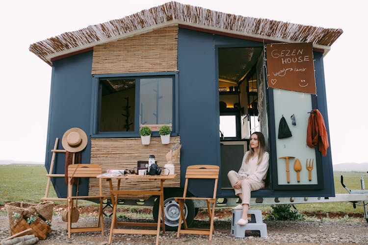 Woman Sitting In A Trailer Converted To A House On Wheels