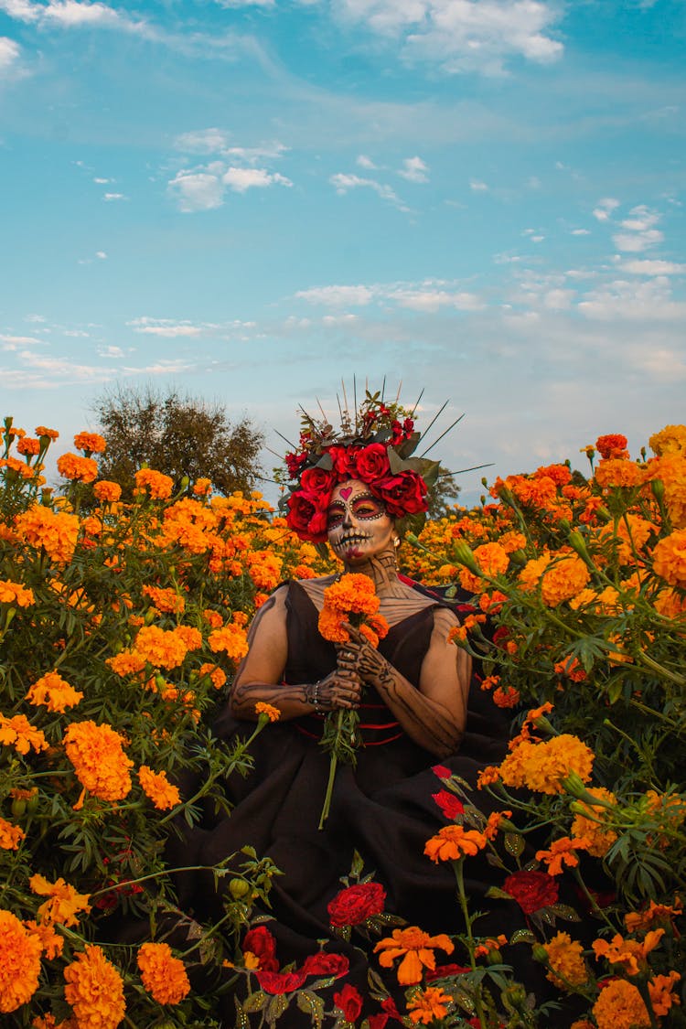 Woman In Makeup For The Day Of The Dead In Mexico Standing On A Field Full Of Flowers 