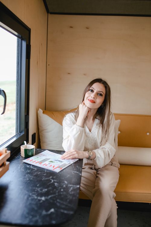 Free Adult woman sitting in a tiny house, smiling and enjoying free time indoors. Stock Photo