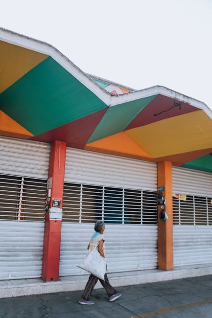A vibrant city street with a colorful building facade and a woman walking by.