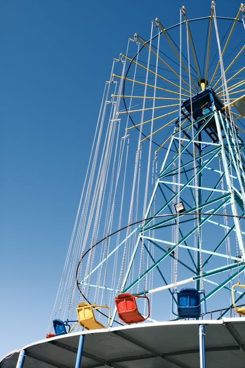 Free A colorful, empty carousel ride against a clear blue sky at an amusement park. Stock Photo