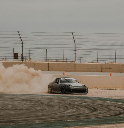 Free A sports car drifting smoothly on a race track, kicking up dust during a motorsport event. Stock Photo