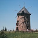 Brown and Gray Windmill on Green Grass Field Under Blue Sky