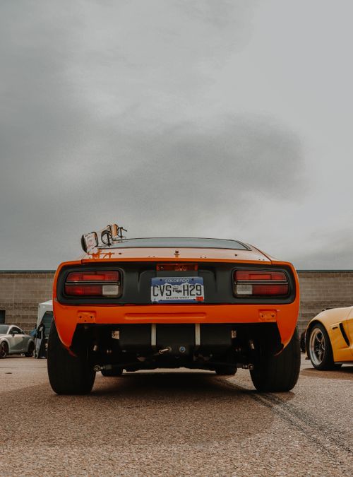Free Rear view of a classic orange sports car parked outdoors, showcasing its design. Stock Photo