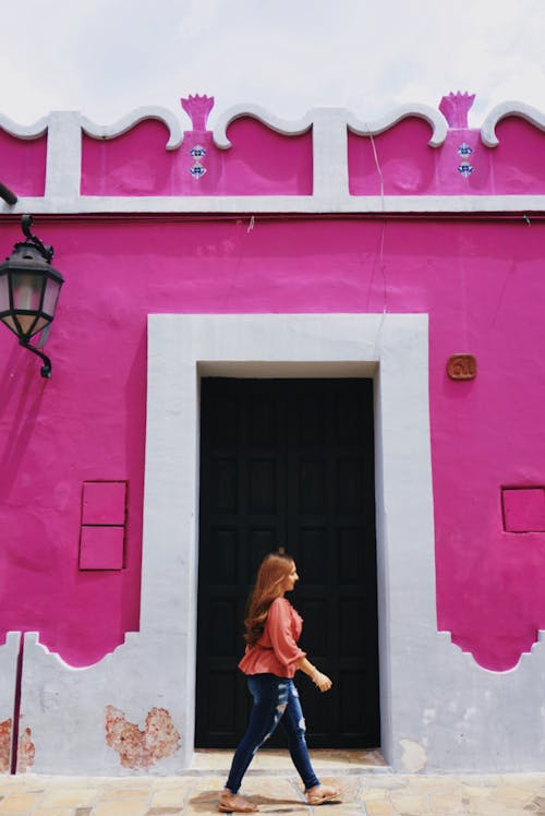 Woman Walking Beside a Purple Wall