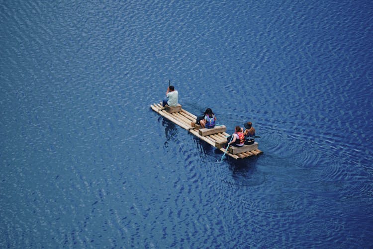 People Riding A Wooden Raft