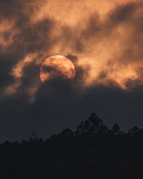 Large Full Moon Behind Clouds at Sunset 