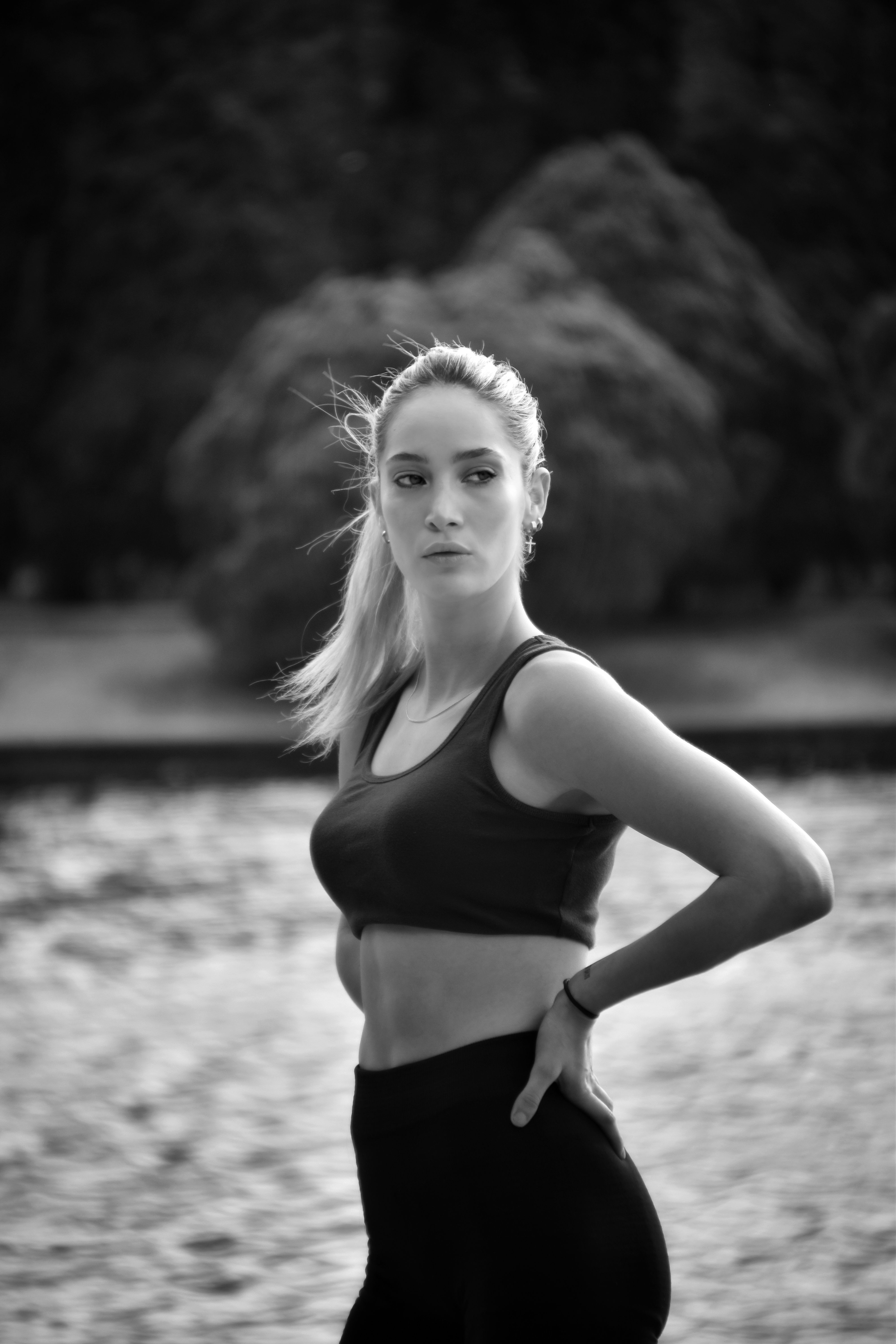 Striking grayscale portrait of a woman in a sports bra outdoors, poised and confident.
