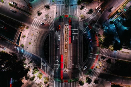 Dynamic aerial view of a bustling roundabout and traffic at night.