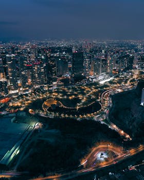 A breathtaking aerial view of a modern cityscape illuminated at night, showcasing vibrant urban life and architecture.